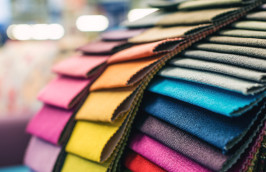 A close-up photo of a piece of a fabric with many droplets of water on it. The fabric is brown with a red stripe.